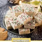 Plate of homemade sugar cookie fudge pieces with festive red and green sprinkles. Surrounded by cookies, pinecones, and holiday decorations. Background lightly dusted with sugar. Text reads: sweetlyspendid.com and Homemade Sugar Cookie Fudge.