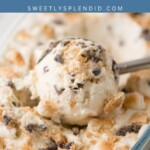 A close-up of s’mores ice cream with chocolate chips and crushed graham crackers in a glass dish, with a metal ice cream scoop lifting a serving. The text reads Smores Ice Cream and sweetlysplendid.com.