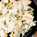 A plate of creamy chicken Alfredo pasta garnished with chopped herbs, served on a black dish with a fork. A label at the top reads creamy chicken alfredo and sweetlysplendid.com.