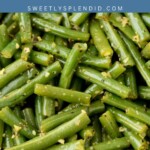 A close-up of cooked garlic green beans coated in rich butter, served in a bowl. Text overlay reads garlic butter green beans and sweetlysplendid.com.