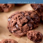 Close-up of chunky triple chocolate cookies with chocolate chips on parchment paper; text above reads Triple chocolate cookies sweetlysplendid.com in white on a blue background.
