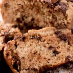 Close-up of sliced chocolate chip banana bread on a cooling rack, with chunks of chocolate on top and around. Text overlay at the top reads chocolate chip banana bread and sweetlysplendid.com.
