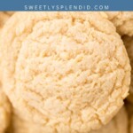 Close-up of several soft, round cookies stacked together. The top of the image has a blue banner with the text easy pudding cookies and sweetlysplendid.com written on it.