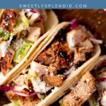 Three chicken street tacos filled with grilled chicken, lettuce, shredded purple cabbage, and crumbled cheese are arranged on a wooden board. A blue banner above reads “Chicken Street Tacos, sweetlysplendid.com.”.