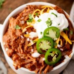 A bowl of food with jalapenos and sour cream.