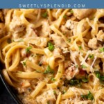 A close-up of creamy chicken Alfredo pasta topped with chopped parsley and grated cheese in a skillet. Text overlay reads chicken ALFREDO with the website sweetlysplendid.com.