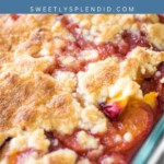 Close-up of a peach cobbler in a glass baking dish, featuring golden, crumbly topping with visible baked peaches and rich juices. A blue banner at the top reads Peach Cobbler and sweetlysplendid.com.