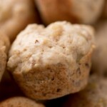Close-up of several banana nut mini muffins with a soft, golden-brown texture. A blue and white label at the top reads “banana nut mini muffins” and “sweetlysplendid.com.”.