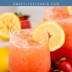 A glass of strawberry lemonade garnished with a lemon slice, surrounded by fresh lemons and strawberries on a wooden board. Text overlay reads “Strawberry Lemonade” and “sweetlysplendid.com.”.