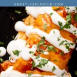 Close-up of beef and bean burritos topped with red sauce, sour cream drizzle, and chopped cilantro on a black plate. A partial lime is visible at the top. Text reads beef & bean Burritos sweetlysplendid.com.