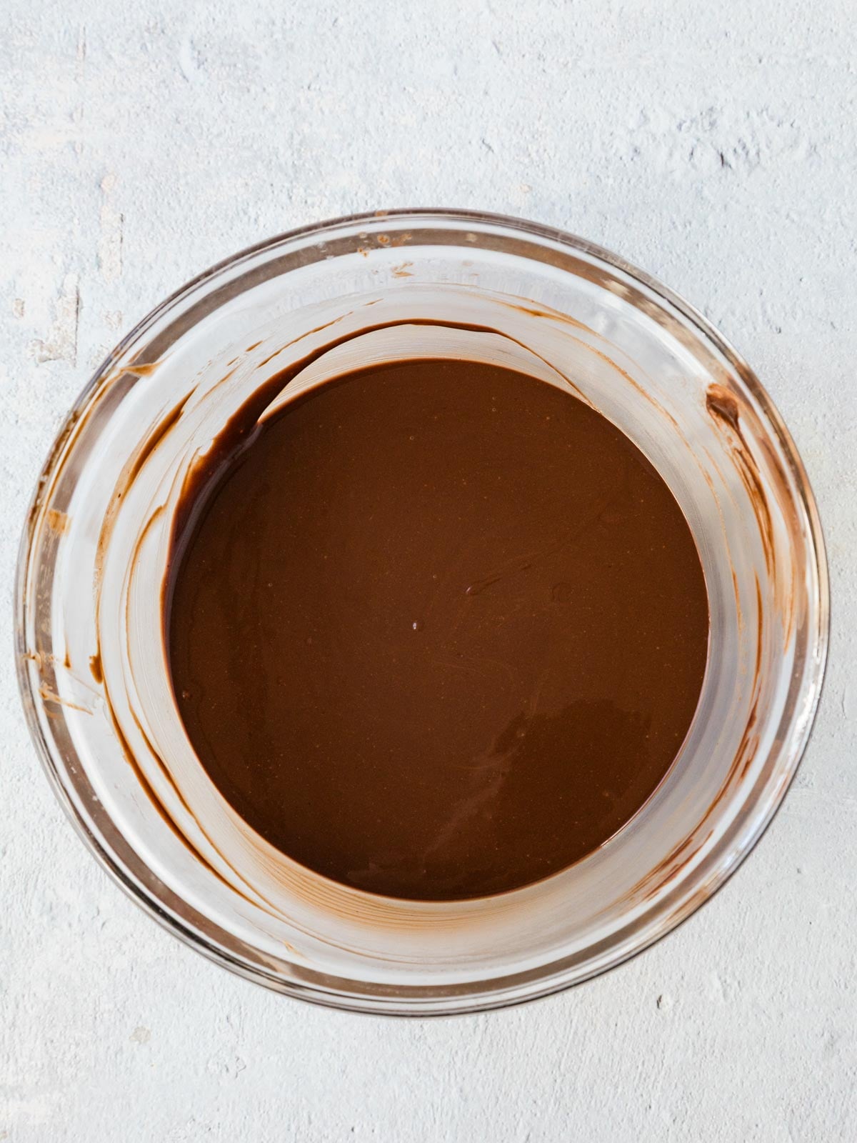 A glass bowl filled with melted dark chocolate.