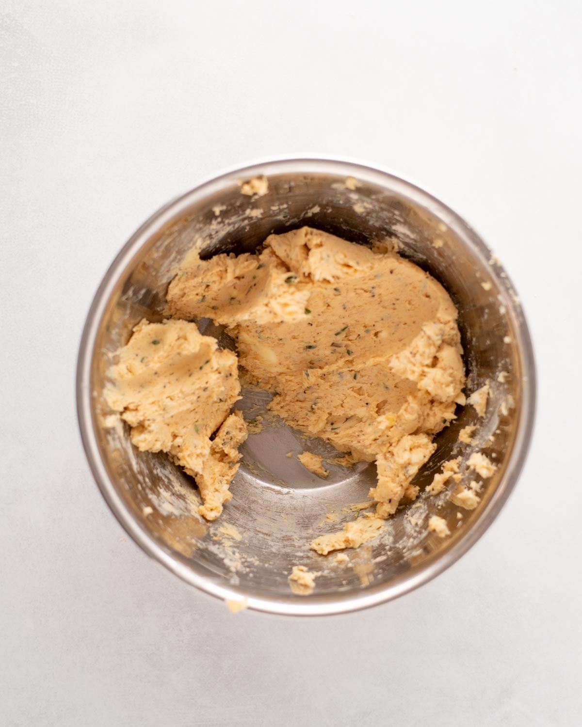 A metal mixing bowl containing a dollop of herb butter.